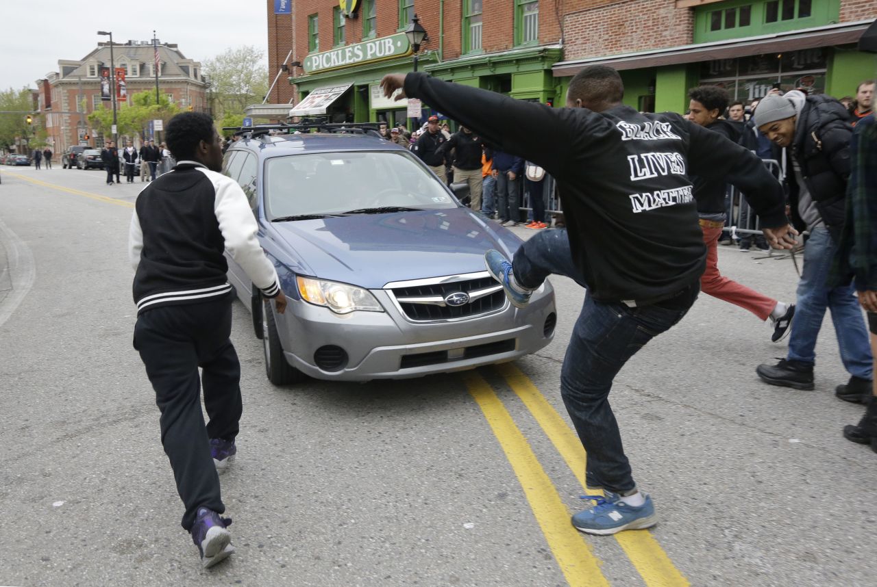 Protesters chase after a car as it drives in reverse after the rally on April 25.