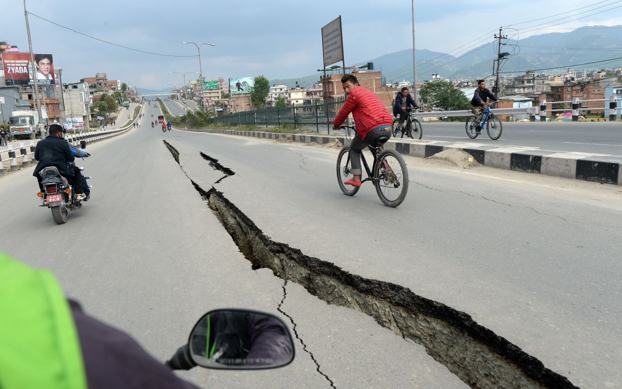 Residents cycle over damaged roads on the outskirts of Kathmandu on Sunday, April 26.
