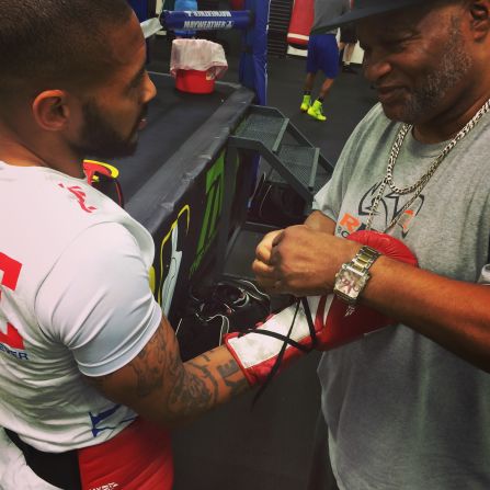 Coach Eddie Mustafa Muhammad -- former light heavyweight world champion and a veteran of 59 professional fights -- ties Theophane's gloves ahead of a sparring session in Mayweather's Las Vegas gym. 