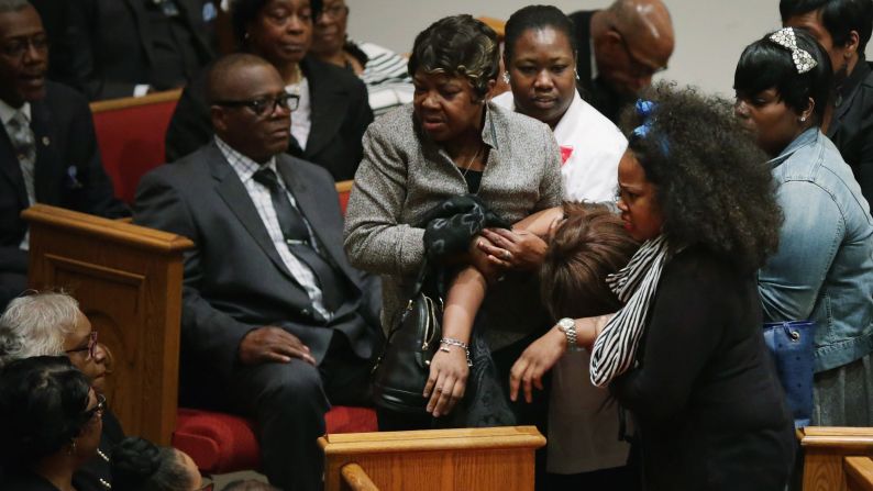 Mourners help a woman who collapsed during the funeral.
