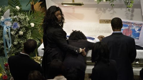 Gray's mother, Gloria Darden, kneels at his casket and embraces him before the start of the funeral.