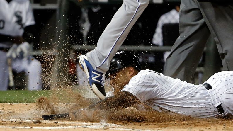Micah Johnson of the Chicago White Sox slides into home plate under Danny Duffy of the Kansas City Royals after being tagged out by Salvador Perez (not pictured) on Friday, April 24, in Chicago.<br />