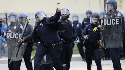 A police officer throws an object at protesters on April 27. 