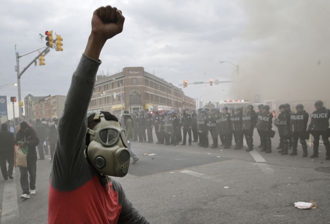 A demonstrator raises his fist as police stand in formation on April 27.