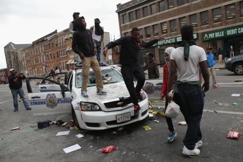 Protesters climb on a destroyed Baltimore Police car in the street near the corner of Pennsylvania and North avenues on April 27.