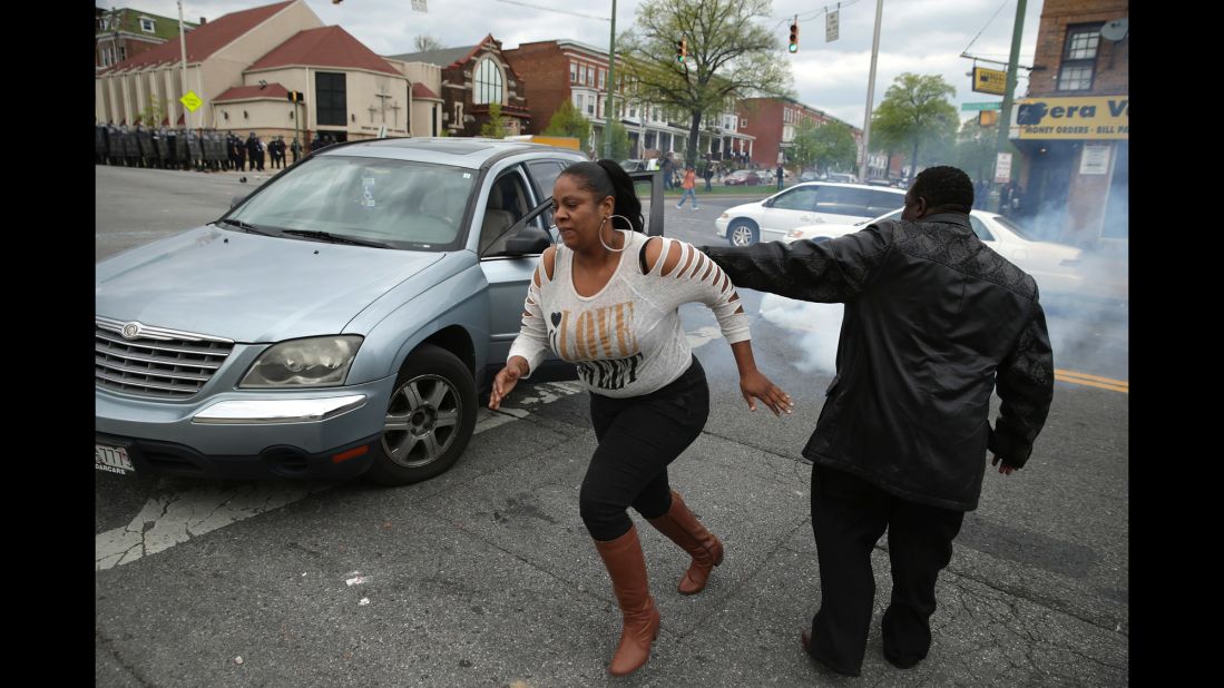 A woman abandons her car in the middle of an intersection as Baltimore Police officers clash with protesters outside the Mondawmin Mall in Baltimore on April 27.