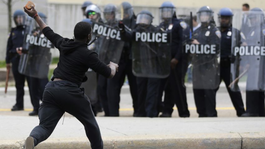 A man throws a brick at police Monday, April 27, 2015, following the funeral of Freddie Gray in Baltimore.
