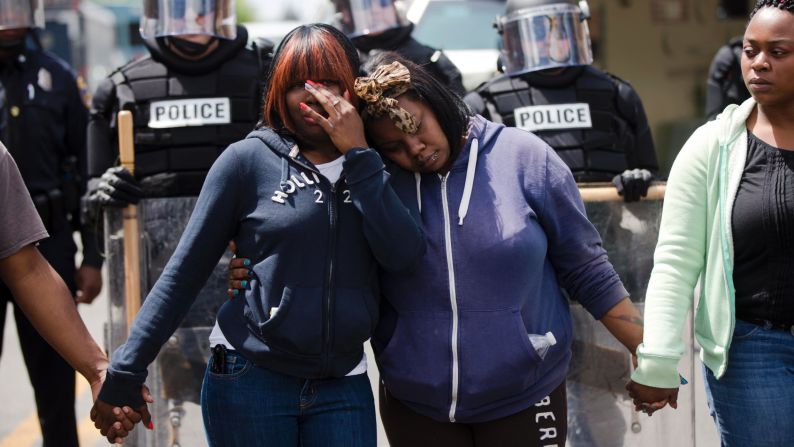 Jerrie Mckenny, left, and her sister Tia Sexton embrace as demonstrators hold hands and sing the hymn "Amazing Grace" in Baltimore on April 28.
