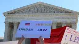 Outside the Supreme Court of the United States, people hold signs calling for "justice under law."