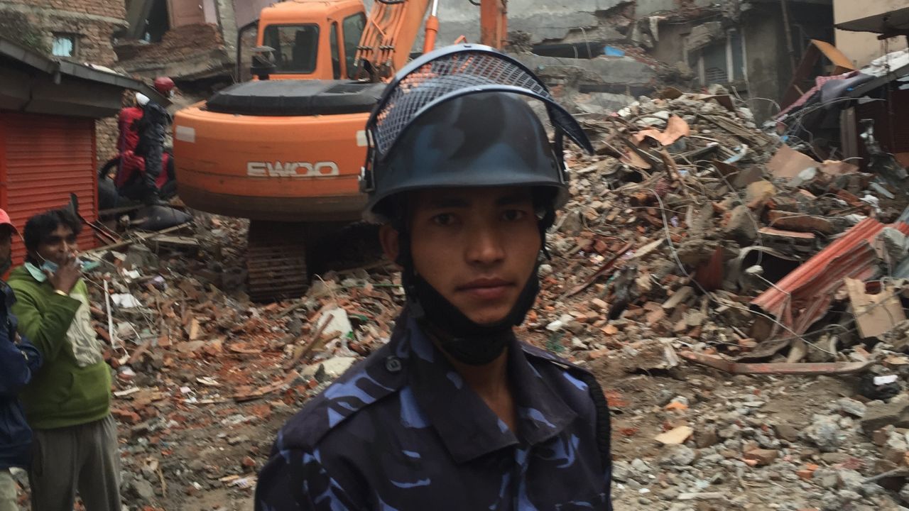 Nepal police officer Tejush Swarnakar stands in front of the rubble of what were six-storey guest houses.