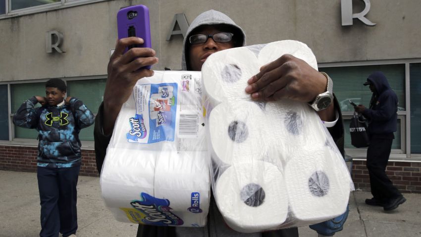 A man holds a cell phone as he carries items, Monday, April 27, 2015, after the funeral of Freddie Gray in Baltimore. Gray died from spinal injuries about a week after he was arrested and transported in a Baltimore Police Department van. (AP Photo/Patrick Semansky)