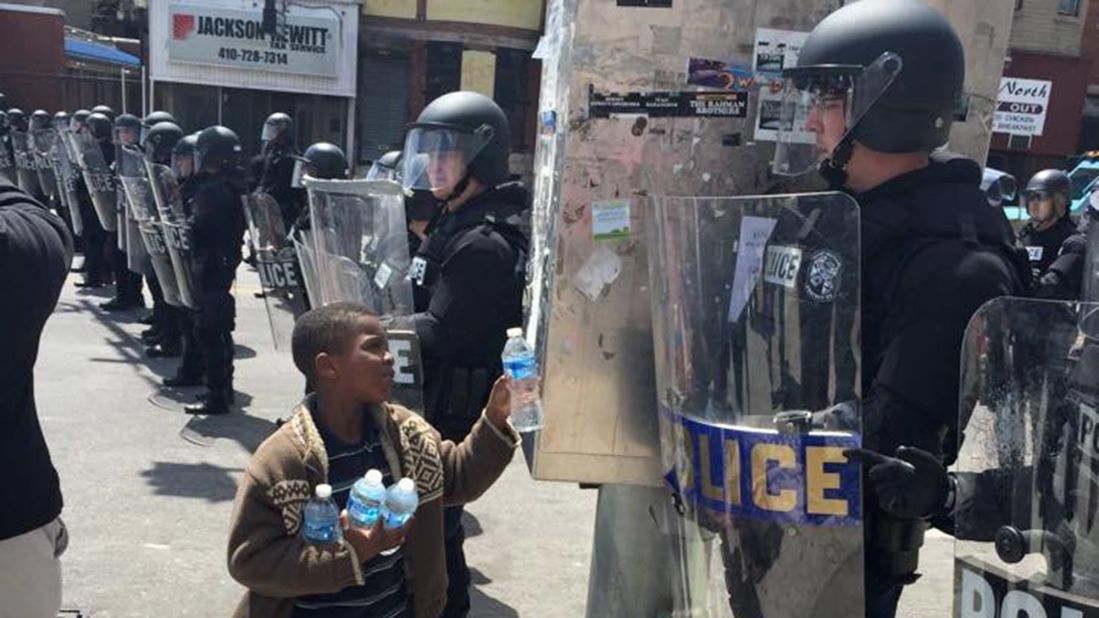 A boy in Baltimore offers water to a police officer on April 28. 
