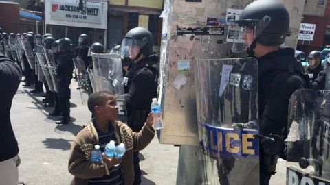 <strong>April 28: </strong>A boy in Baltimore offers water to a police officer. Riots broke out throughout the city less than a week after <a href="http://www.cnn.com/2015/04/27/us/gallery/freddie-gray-funeral/index.html" target="_blank">25-year-old Freddie Gray died in police custody.</a> Gray, a black man, was arrested on April 12. According to his attorney, he died a week later from a severe spinal cord injury he received while in police custody. The case raised long-simmering tensions between police and residents, and <a href="http://www.cnn.com/2015/09/02/us/baltimore-freddie-gray-death-case/" target="_blank">six police officers were eventually charged</a> in connection with Gray's death.