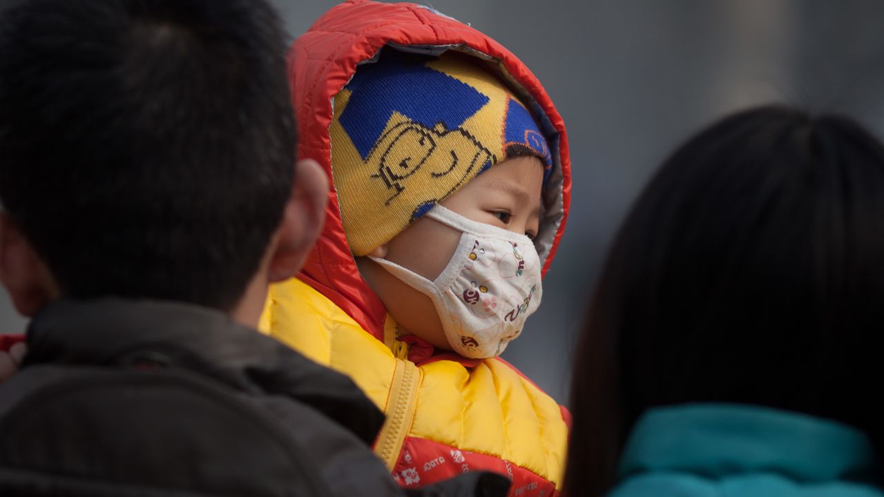 An infant wearing a mask was carried along a street in severe pollution in Beijing on January 12, 2013.