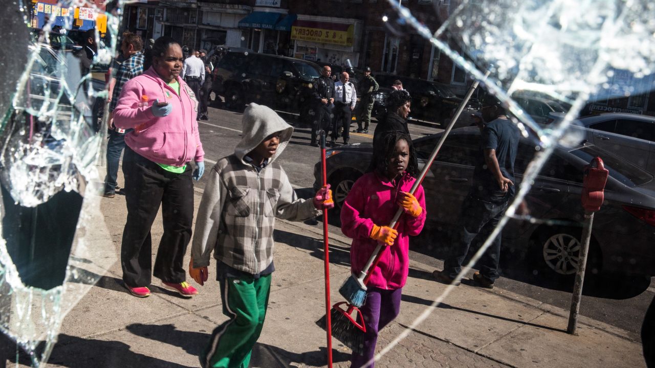 People helping clean debris are seen in the reflection of a broken window on April 28.
