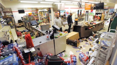 Employee Sam Wirtz, left, surveys the damage to his store that came during the unrest on Monday, April 27.