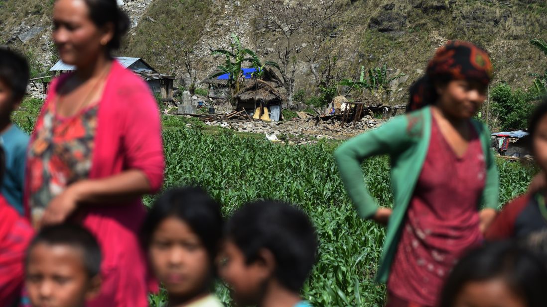 People await aid from an Indian army helicopter in front of damaged homes in Kulgaun, Nepal, on May 1.