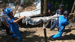 Caption:Rescue workers carry a body uncovered at the site of a mass grave at an abandoned jungle camp in the Sadao district of Thailand's southern Songkhla province bordering Malaysia on May 1, 2015. Authorities in Thailand uncovered a mass grave in an abandoned jungle camp on May 1 believed to contain the remains of migrants from Myanmar and Bangladesh, a grisly find in a region notorious for people smuggling routes. The border area with Malaysia is notorious for its network of secret camps where smuggled migrants are held, usually against their will until relatives pay up hefty ransoms. AFP PHOTO (Photo credit should read STR/AFP/Getty Images)