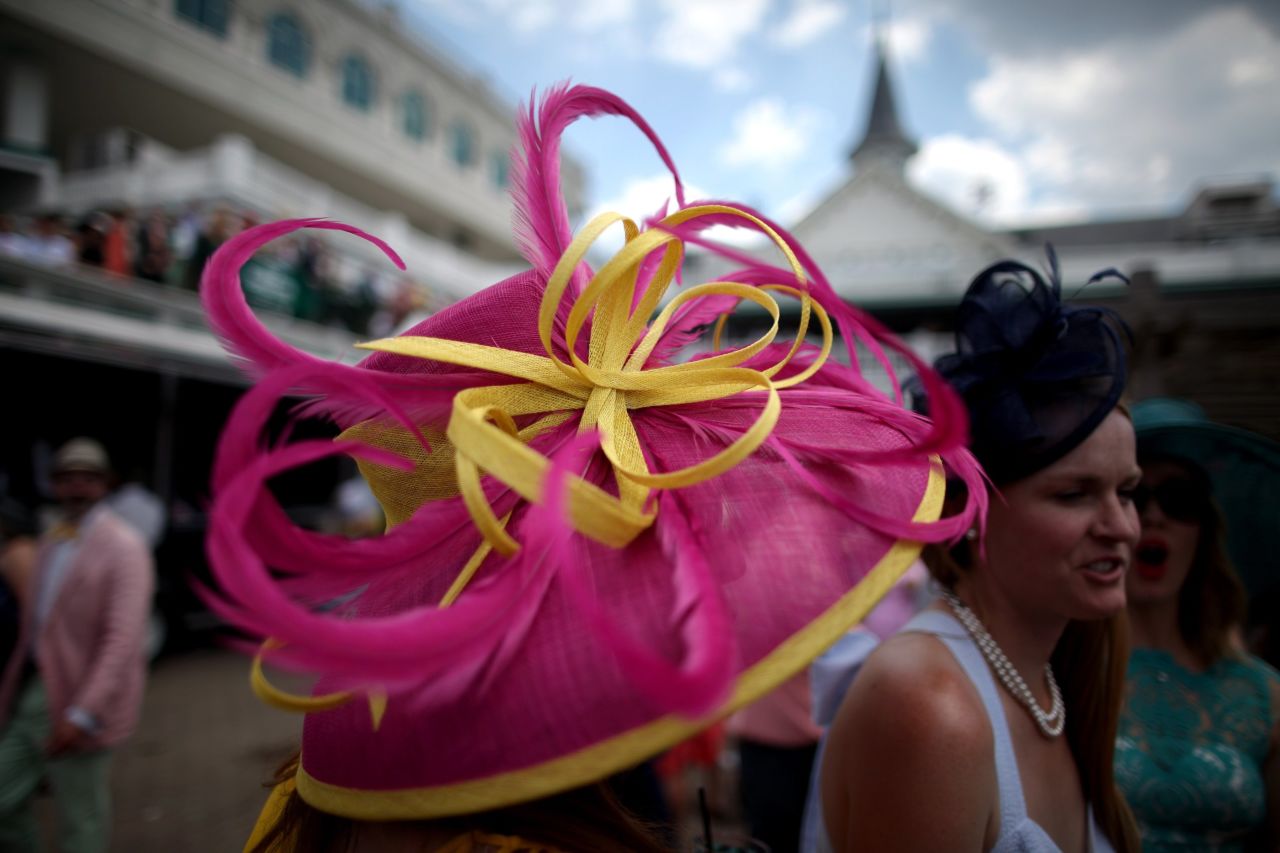 A woman wears an eye-catching pink and yellow hat prior to the Derby. Advice from the Kentucky Derby: If your hat is having a pattern party, keep the dress design simple.