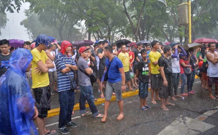 Fans brave a heavy downpour as they watch a live telecast of fight in Marikina, Philippines.