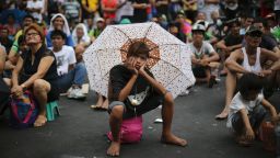 A Filipino uses an umbrella to shield him from the sun as they watch a live satellite feed of the welterweight title fight between Filipino boxing hero Manny Pacquiao and Floyd Mayweather Jr. during a free public viewing in downtown Manila, Philippines on May 3.