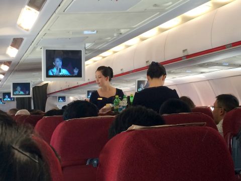The flight attendants on Air Koryo serve refreshments as monitors show a North Korean televised concert mainly featuring patriotic songs about the military.
