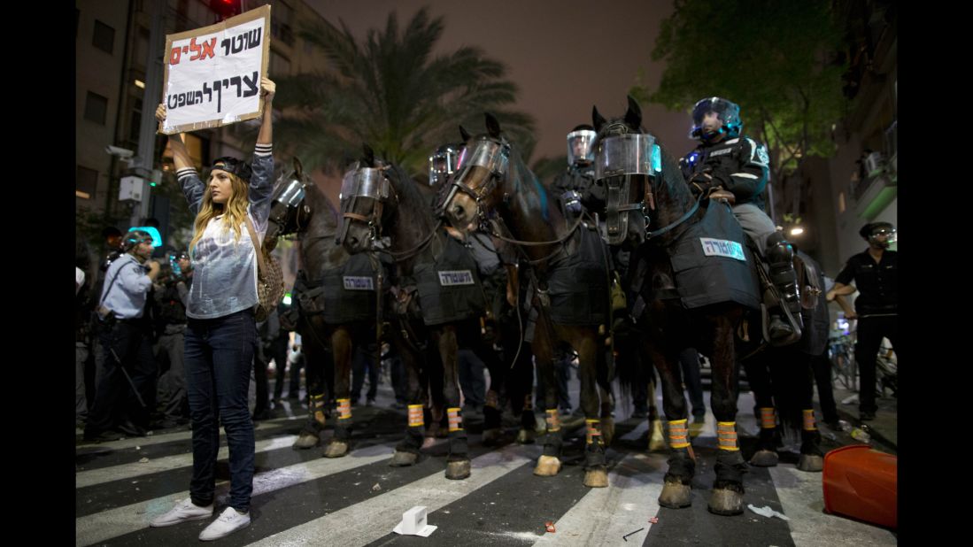 An Israeli protester holds a sign reading "violent policemen should be sentenced" during clashes between protesters and Israeli riot police in Tel Aviv on Sunday, May 3. The protest was sparked after video emerged showing what appeared to be two police officers beating a uniformed Israeli soldier of Ethiopian origin.