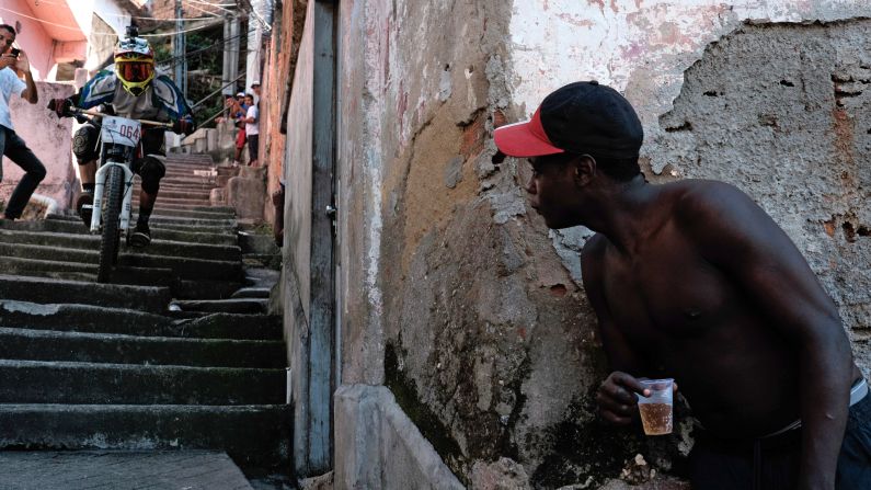 A resident watches a competitor go down the steps of an alley during the Favelas Mountain Bike Circuit at Turano shantytown in Rio de Janeiro on Sunday, May 3. The competition started in March and will be competed in eight stages until November in downhill and cross-country categories.
