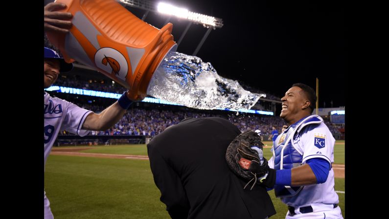 Catcher Salvador Perez, right, of the Kansas City Royals takes cover from teammate Erik Kratz behind broadcaster Joel Goldberg on Friday, May 1, in Kansas City, Missouri.