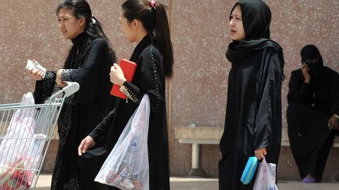 Domestic workers  carry shopping bags as they walk out of a mall in Riyadh, on June 12, 2013.