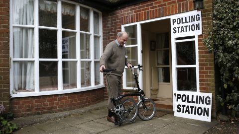 A member of the public unfolds his bike after voting at Three Oaks, a residential house turned polling station, in Bramshill, England.