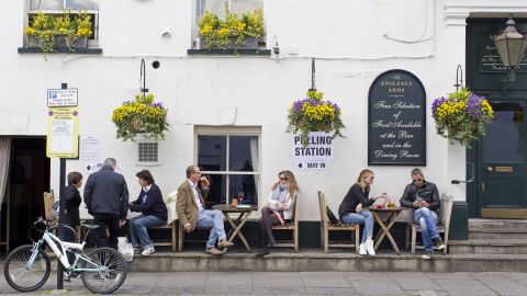 People sit outside the Anglesea Arms pub in London. The pub is being used as a polling station.
