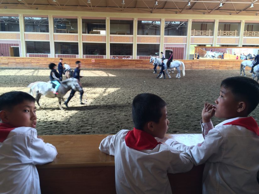 North Korean students watch riding lessons at a new equestrian center designed by Supreme Leader Kim Jong Un. The facility was formerly used for military training.