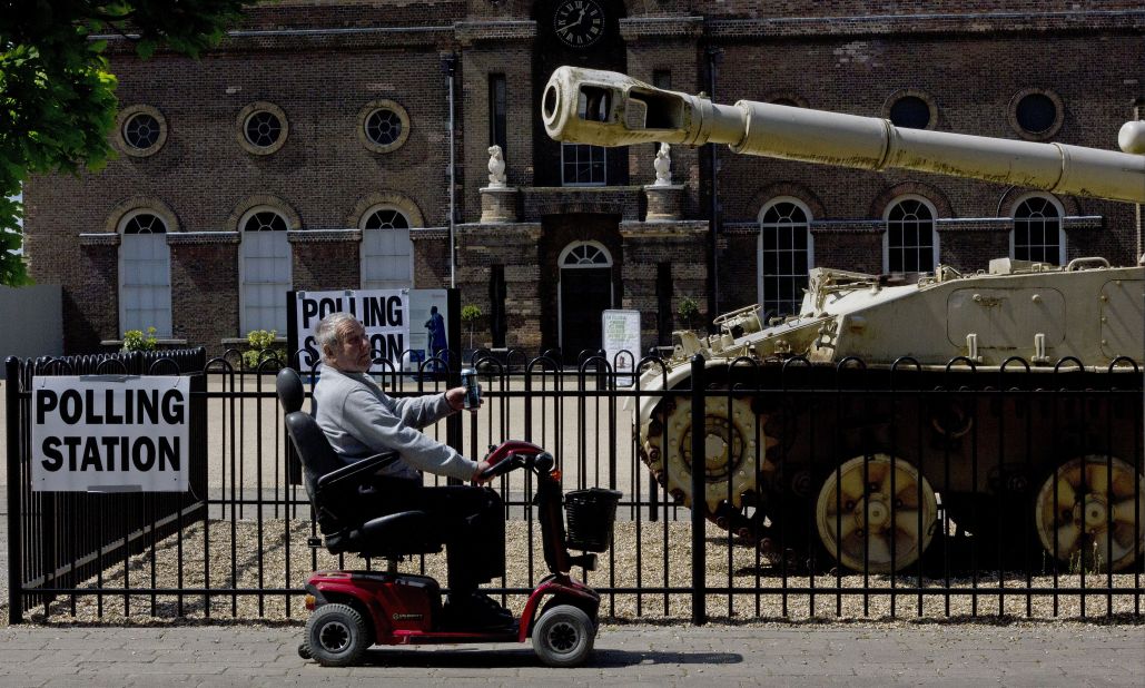A man rides a mobility scooter past a an armored vehicle outside the polling station at the Greenwich Heritage Centre in London.