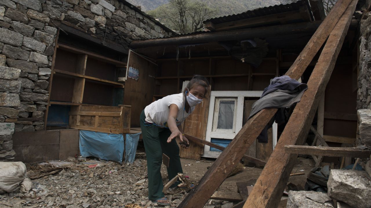 A girl helps clean out rubble from her family home in the village of Kyongma. In some villages, almost every house was damaged in the massive quake.