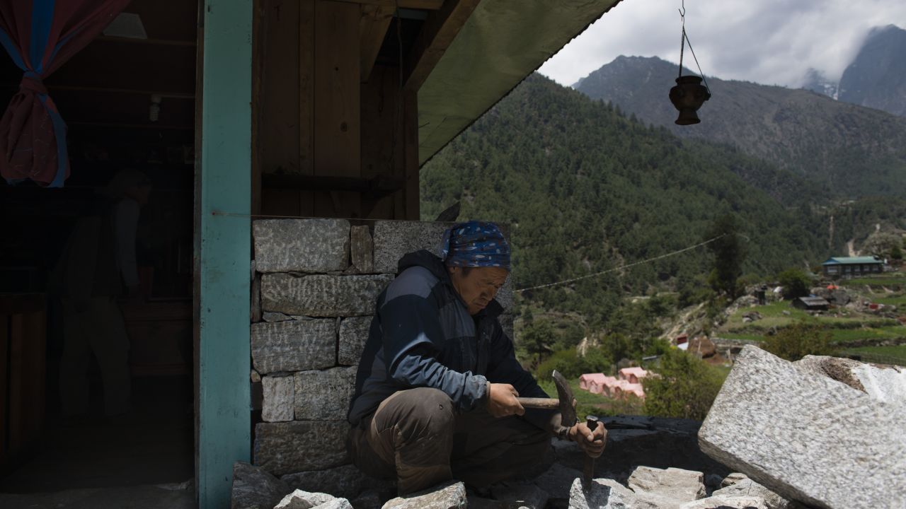 A Sherpa man cuts stone to try rebuilding his damaged house. Many of the houses in this part of Solokhumbu District were built with stone, cement and wood and sustained major damage.