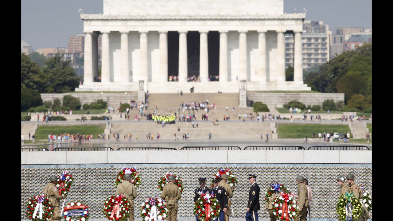 Soldiers dressed in World War II-era uniforms place wreaths in front of the Freedom Wall at the World War II Memorial in Washington.