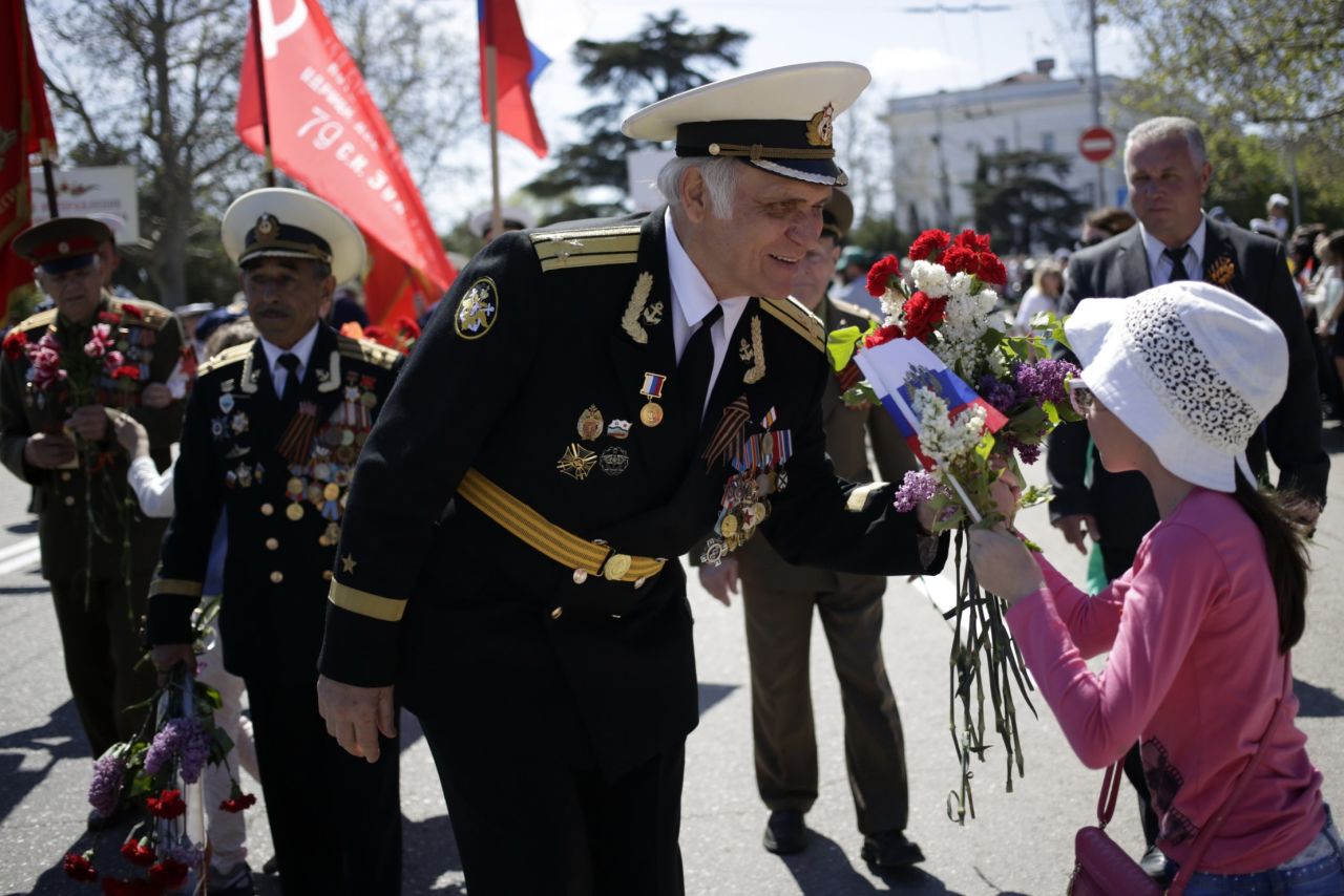 A Crimean veteran accepts flowers from a young girl during a march in central Sevastopol on May 9. Friction continues between Russia and Western nations that were allied with the former Soviet Union during World War II, stemming from Russia's recent actions involving Ukraine, including its annexation of Crimea last year.