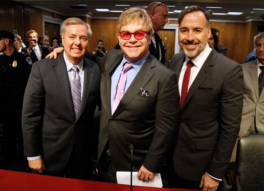 Graham; Sir Elton John, center; and filmmaker and John's husband, David Furnish, pose after testimony at a U.S. Senate hearing on the global fight against AIDS on May 6, 2015. Graham and Democratic Sen. Patrick J. Leahy of Vermont hosted John as part of their bipartisan effort to combat HIV infection.