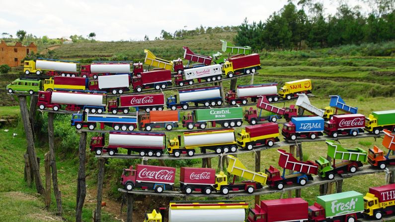 A colorful display of toy trucks is a quirky sight in the green countryside.