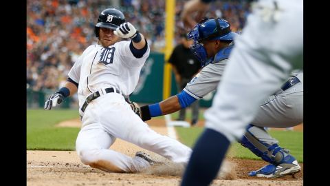 Detroit's Andrew Romine slides safely into home plate, beating the tag of Kansas City's Salvador Perez on Friday, May 8.