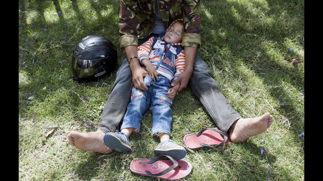 A boy sleeps in his father's lap after they moved to an open area in the Tundikhel area of Kathmandu on May 12.