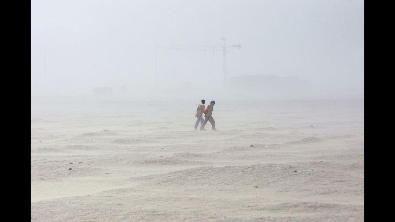 Two men walk through a sandstorm in Abu Dhabi.
