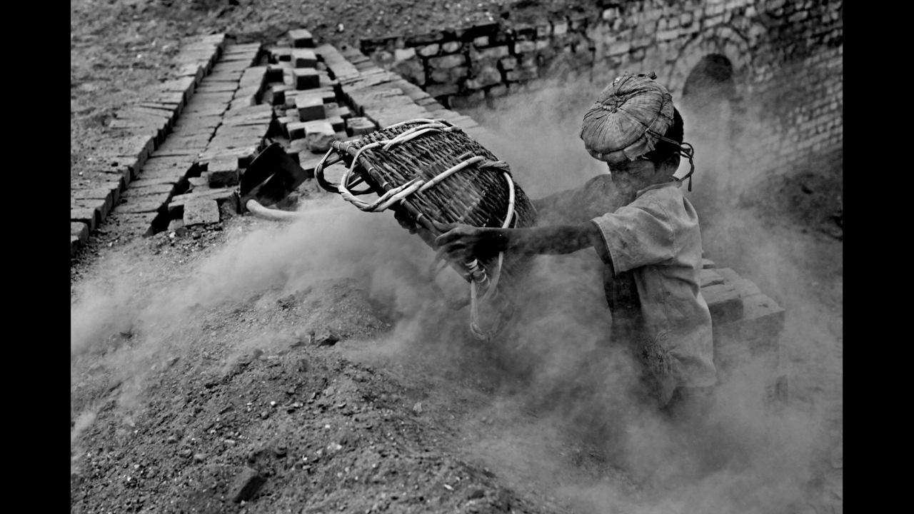 Shafik works above a pile of burning bricks in the brickyard.