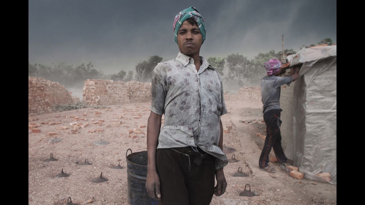 A worker poses for a photo before a sandstorm hits a brick factory in Dhaka, Bangladesh.