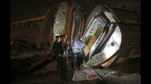 Police stand between two overturned train cars on Tuesday, May 12.