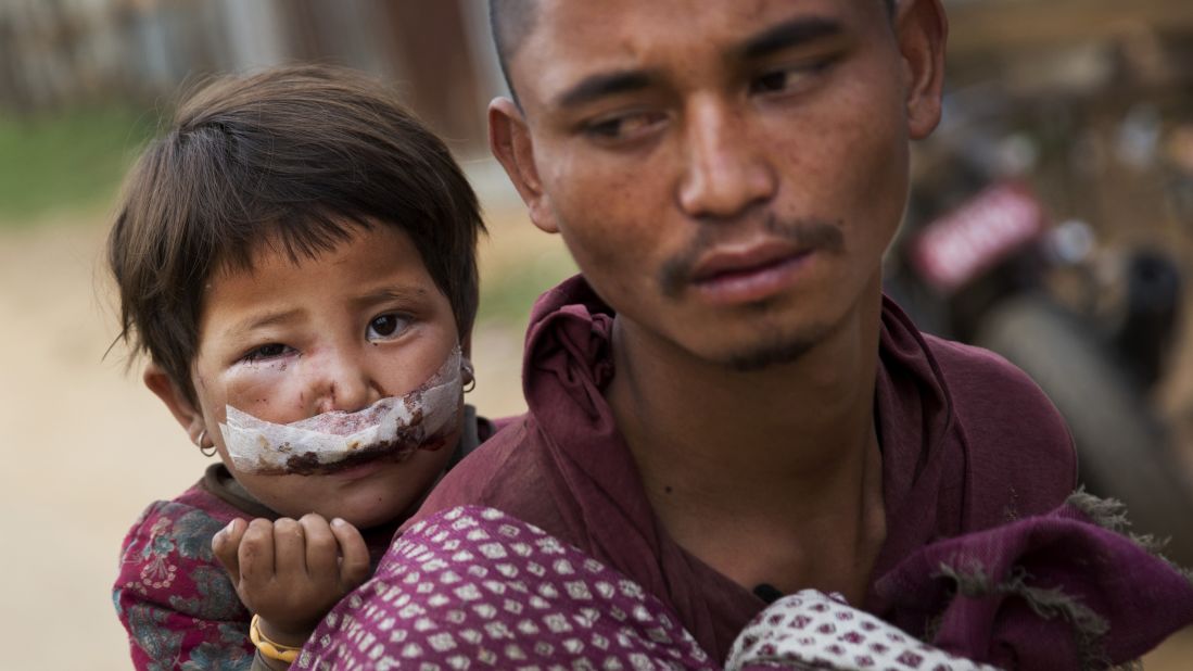 A man carries his child to a camp for displaced people in Chautara on May 13.