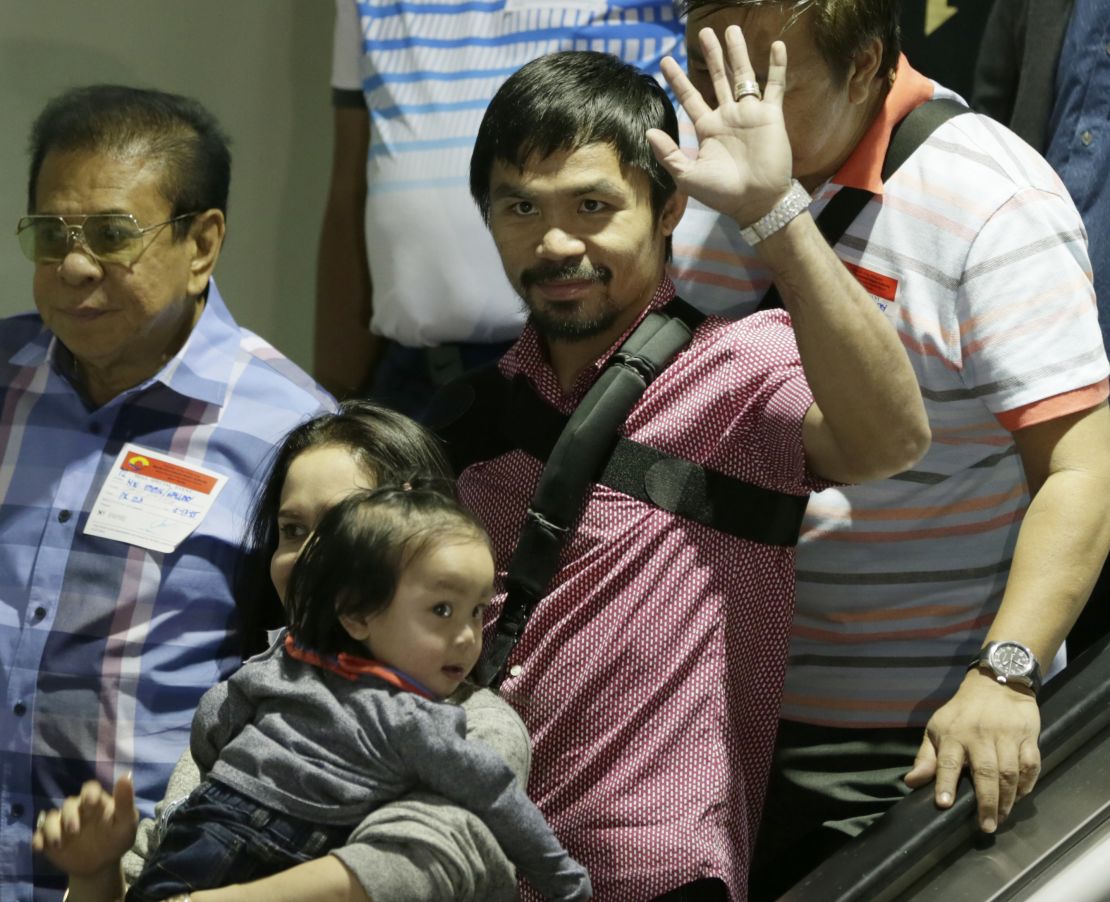 Filipino boxer Manny Pacquiao waves to the crowd upon arrival with his family including his wife Jinkee and youngest son Israel (bottom left) on May 13 at the airport in the Philippines.