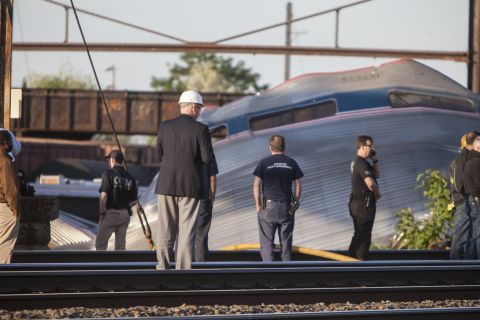 Rescue crews and investigators inspect the crash site on May 13. The impact of the crash tore cars apart, sending seven of them flying from the tracks. It also left the engine a mangled mess.