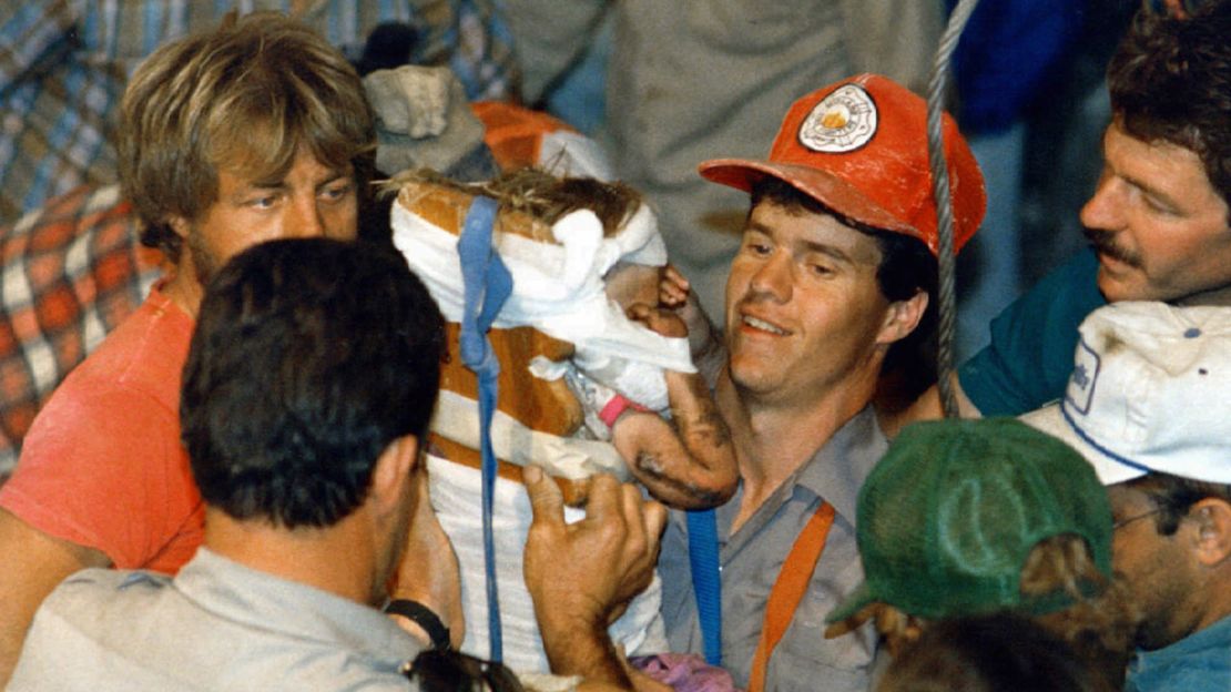 A rescue worker carries18-month-old Jessica McClure to safety in Midland, Texas after she was trapped for 58 hours after she plunged 22 feet into an abandoned water well.